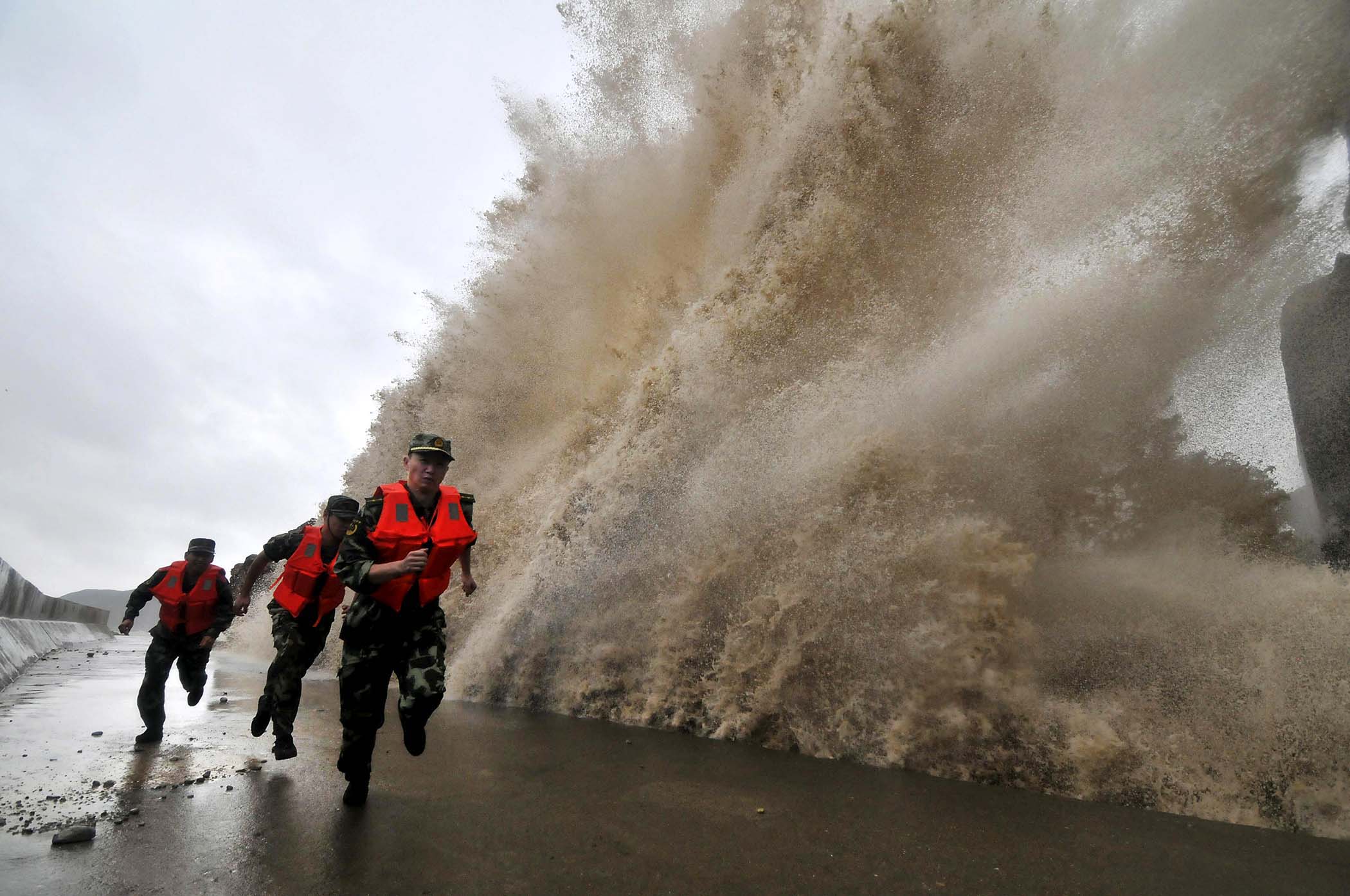 Frontier soldiers run as a storm surge hits the coastline under the influence of Typhoon Fitow in Wenling, Zhejiang province