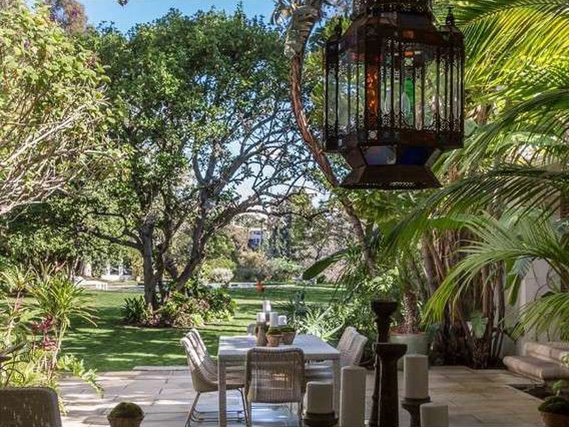 And the backyard has a dining terrace that is filled with greenery. 