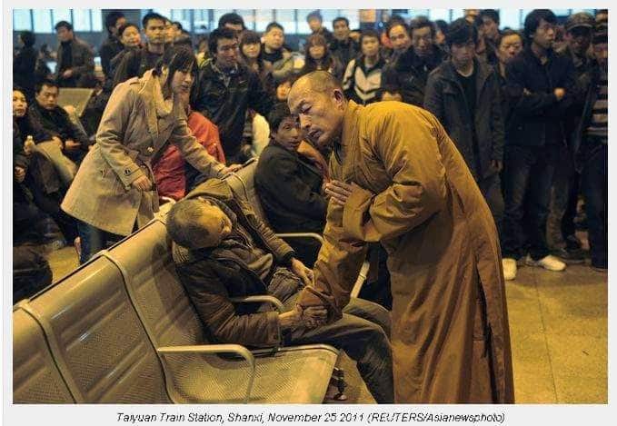 a monk prays for a dead man in the station hall of the shanxi taiyuan train station china