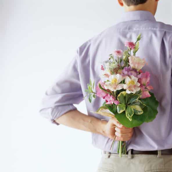 Man Holding a Bouquet of Flowers Behind His Back