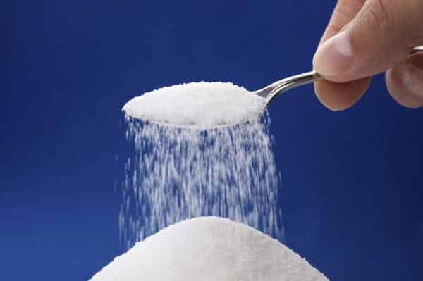 Heap of sugar and pouring more from a spoon