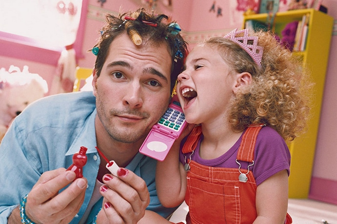 Daughter playing with father with hair curlers and nail polish