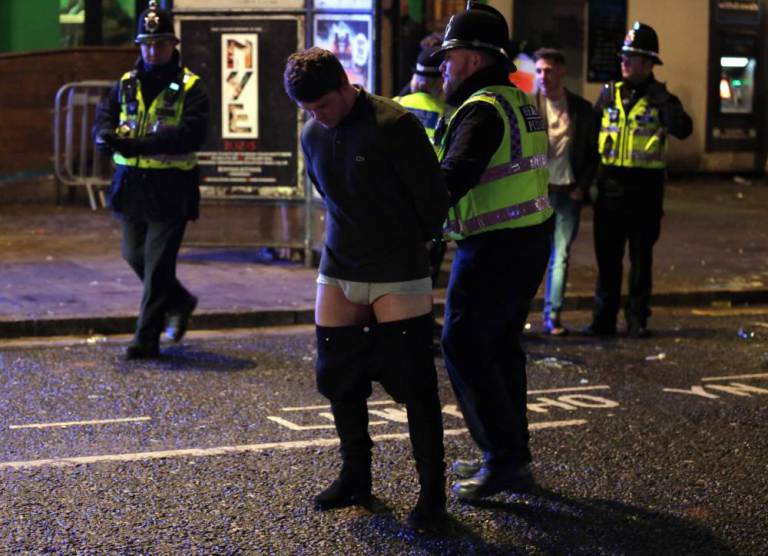 Pictured: A man whose trousers are falling down is detained by police officers Friday 01 January 2016 Re: New Year revellers in Wind Street, Swansea, south Wales.