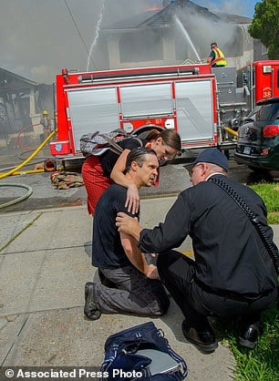 Writer and actor Gideon Hodge , front left, speaks with a fire official after running into his burning home to save his laptop, Thursday, Sept. 15, 2016, in New Orleans, La. Hodge rushed into the structure – past firefighters yelling at him to stop – to grab his laptop, which he said had two completed novels on it. (Matthew Hinton/The Advocate via AP)