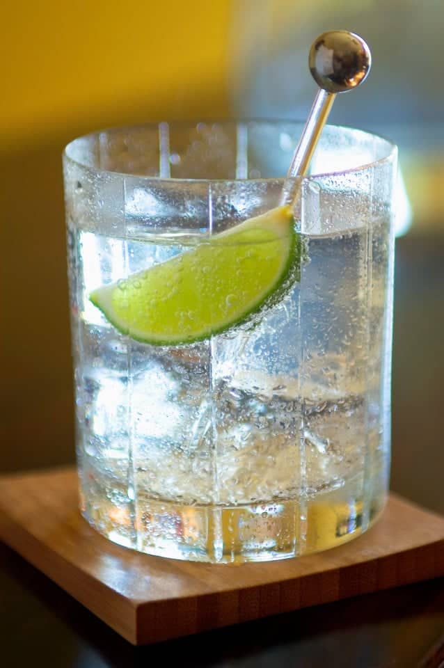 Gin and tonic with ice cubes and lime wedge