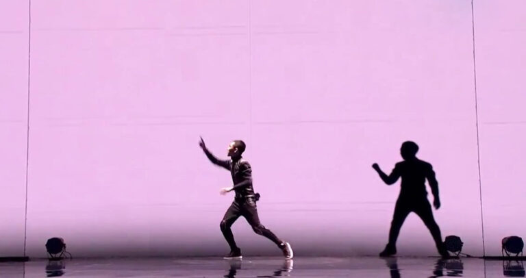 Χορευτής εκτελεί εξαιρετικά συγχρονισμένη χορογραφία με φως από προτζέκτορες.