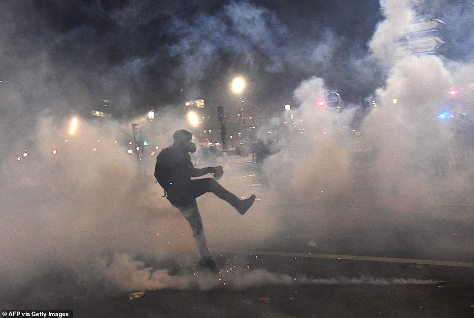 36209690 8996437 amid a cloud of tear gas a protester kicks a canister back towar a 32 1606598224628