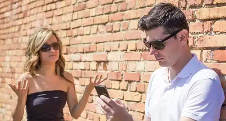 angry man looking phone displeased young woman up her hands front wall background focus man.jpg 1