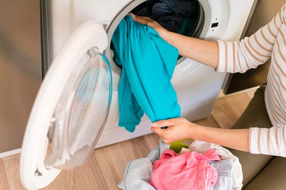 hands taking laundry out washing machine