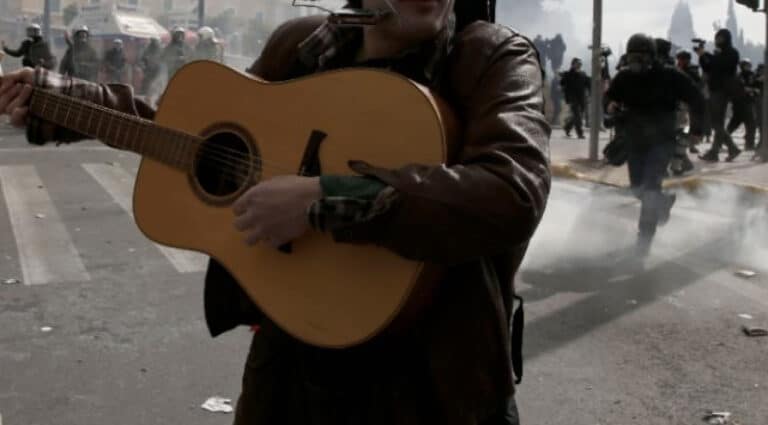 Τέμπη: Μουσικός παίζει κιθάρα εν μέσω των σοβαρών επεισοδίων στο Σύνταγμα