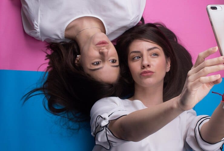 high angle view female friends taking selfie while lying colored background 1048944 5624321