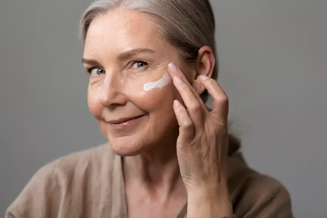 side view smiley woman applying face cream 1