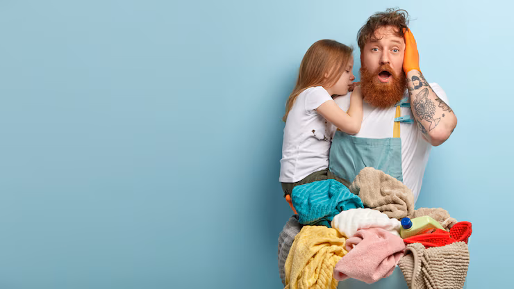 overwhelmed surprised bearded ginger man keeps jaw dropped keeps hand head carries crying daughter feels puzzled has wash laundry stands against blue wall with blank space 273609 26470