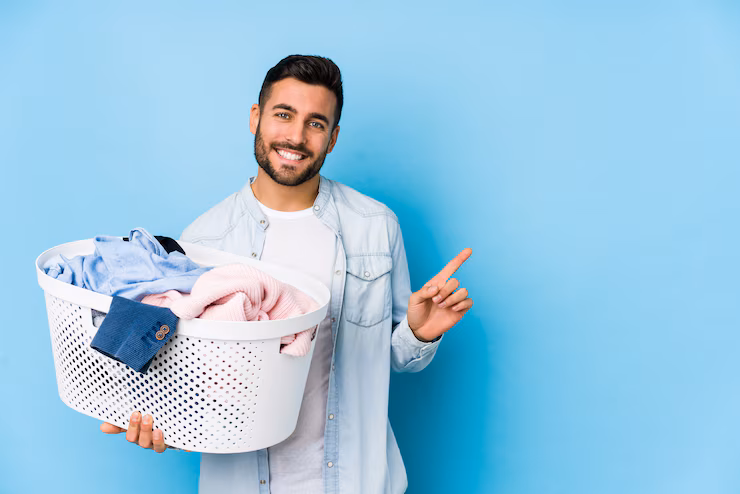 young handsome man doing laundry isolated smiling pointing aside showing something blank space 1187 121623