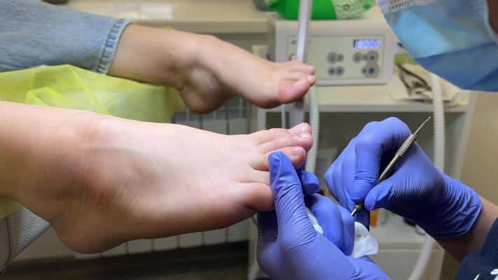 a pedicure master does cleaning and massage pedicure to a young beautiful girl with a small foot caring for female beauty in a beauty salon during a procedure skin of feet and toes close up video
