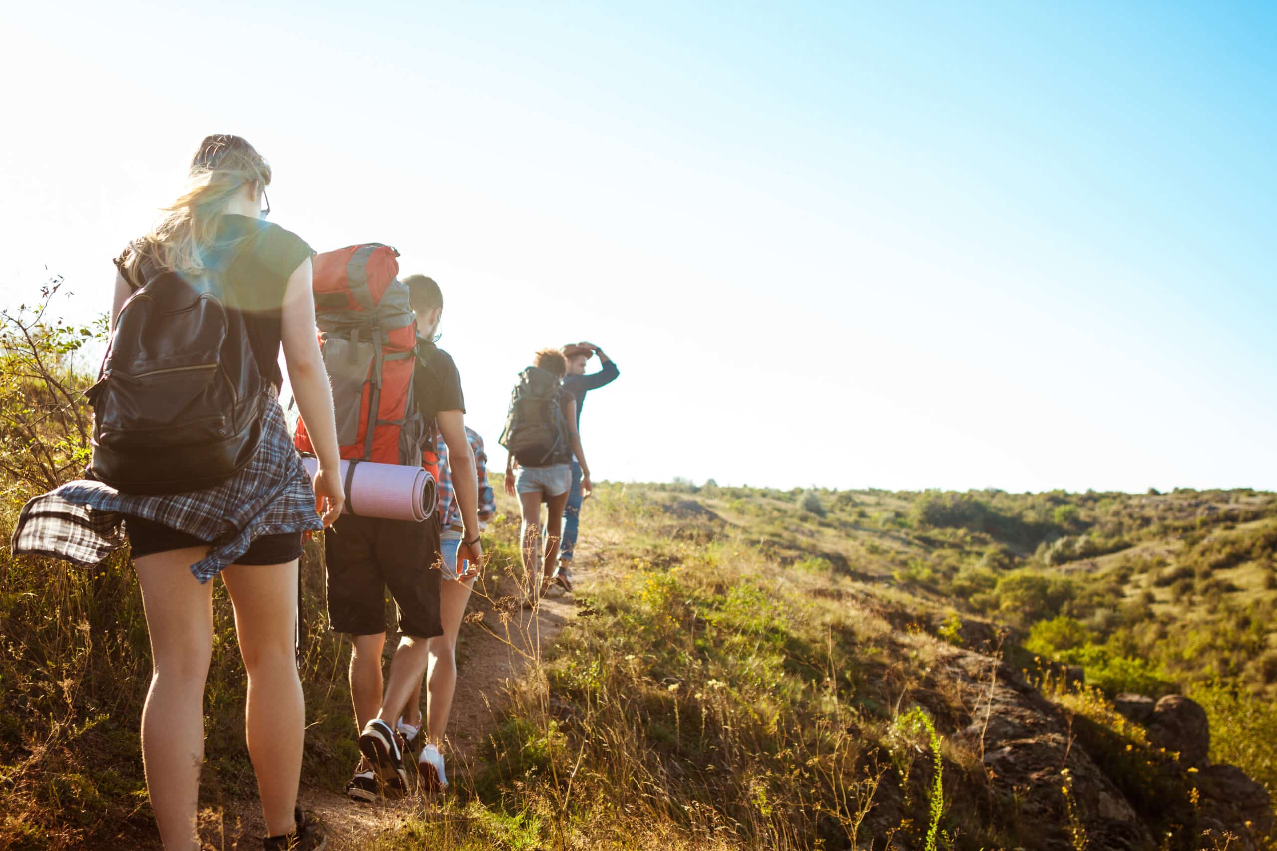 young beautiful friends travelers with backpacks walking canyon scaled