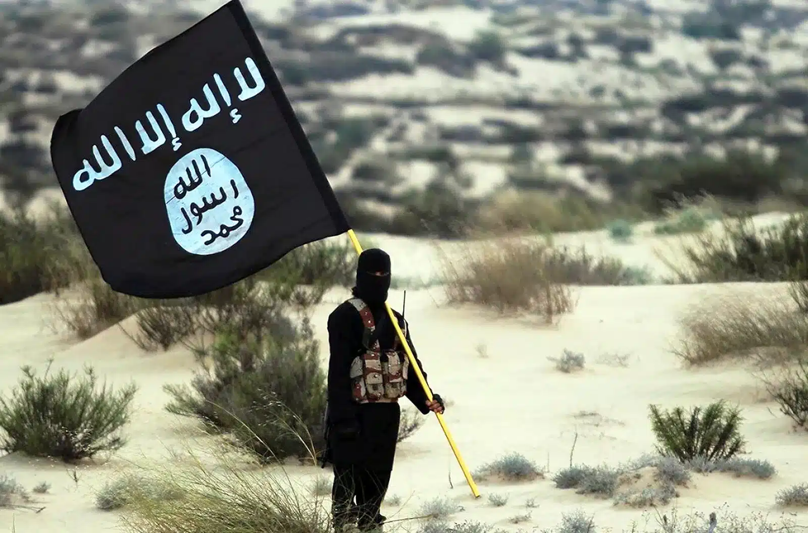 masked islamic state soldier poses holding the isil banner in the desert 2015
