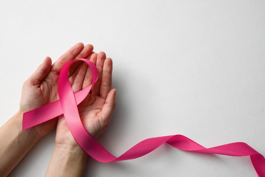 woman holding pink ribbon on white background