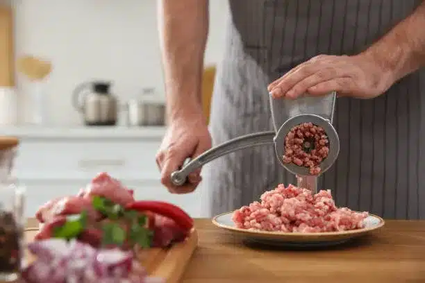 man using hand meat grinder in k